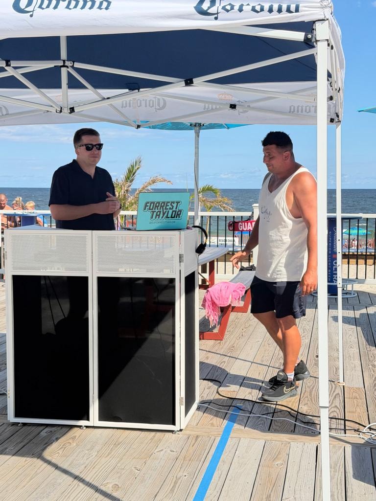 DJ setup under a Corona tent at a boardwalk event