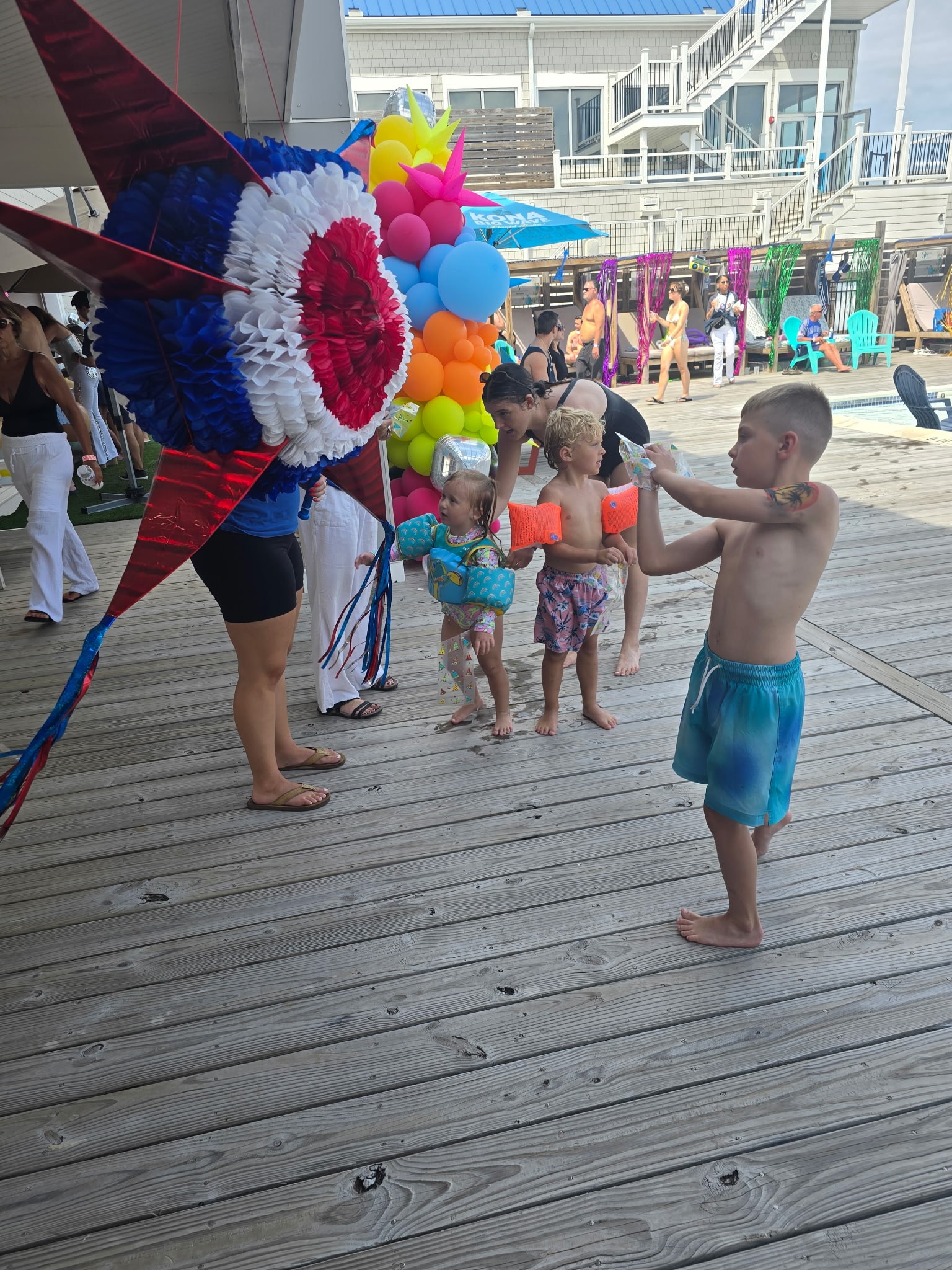 Kids at a pool party with a piñata
