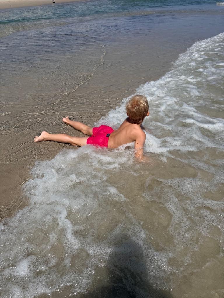 Child playing in the ocean waves at the private beach