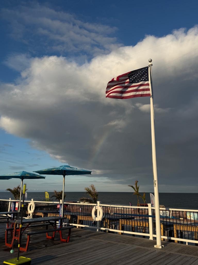 American flag flying over the boardwalk deck with a rainbow
