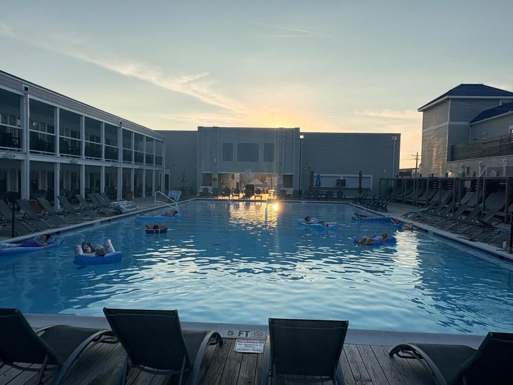 Resort pool at sunset with guests floating on rafts